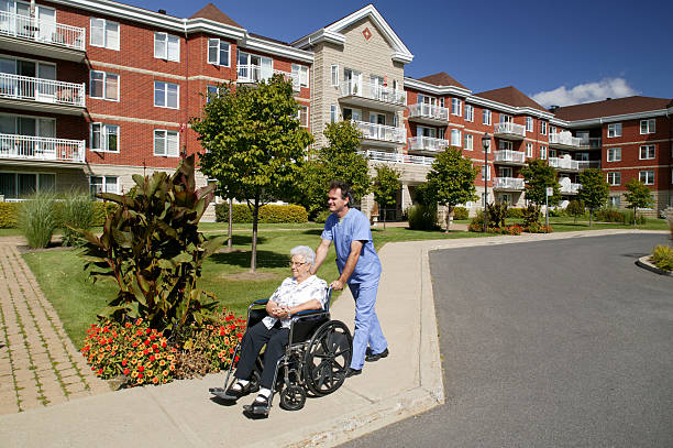 enfermeira ou o médico levando uma cadeira de rodas ao ar livre - lar de idosos - fotografias e filmes do acervo