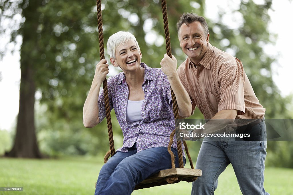 Senior hombre empujando a su esposa en un columpio - Foto de stock de 60-69 años libre de derechos