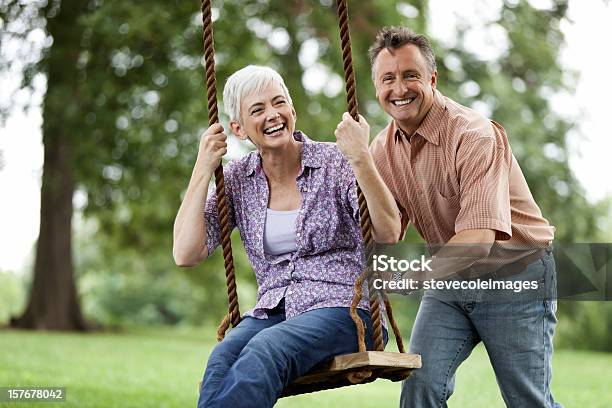 Uomo Anziano Spingendo La Moglie Su Un Altalena - Fotografie stock e altre immagini di 60-69 anni - 60-69 anni, Felicità, Relazione di coppia