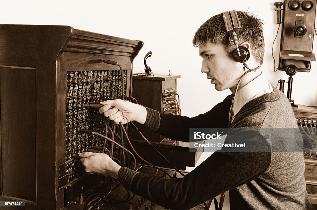 Telephone operator using antique switchboard Young man operating vintage telephone equipment Old-fashioned Stock Photo
