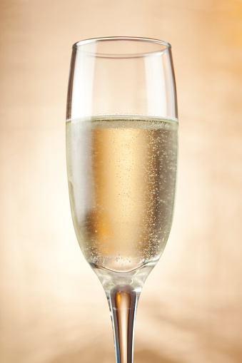 Shot of four full champagne flutes with bubbles on a glass table against black background with copy space