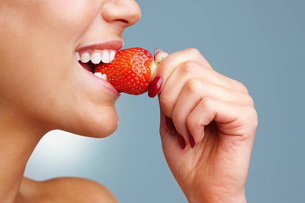 Macro vue d'une jolie jeune femme mangeant des fraises - Photo