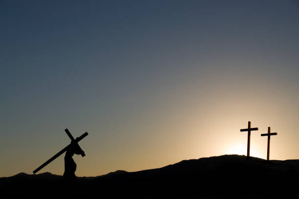 The figure of Jesus Christ carrying the cross up Calvary on Good Friday. The sky is dark and the theives crosses are on Calvary.