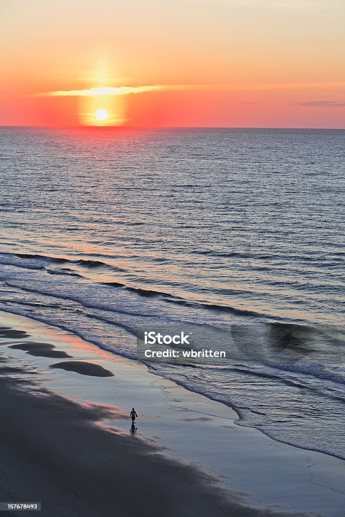 Solitary walker with ocean sunrise or sunset  Beach Stock Photo