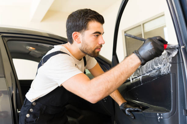 istock Young Mexican worker cleaning car door interior at workshop 1576787657