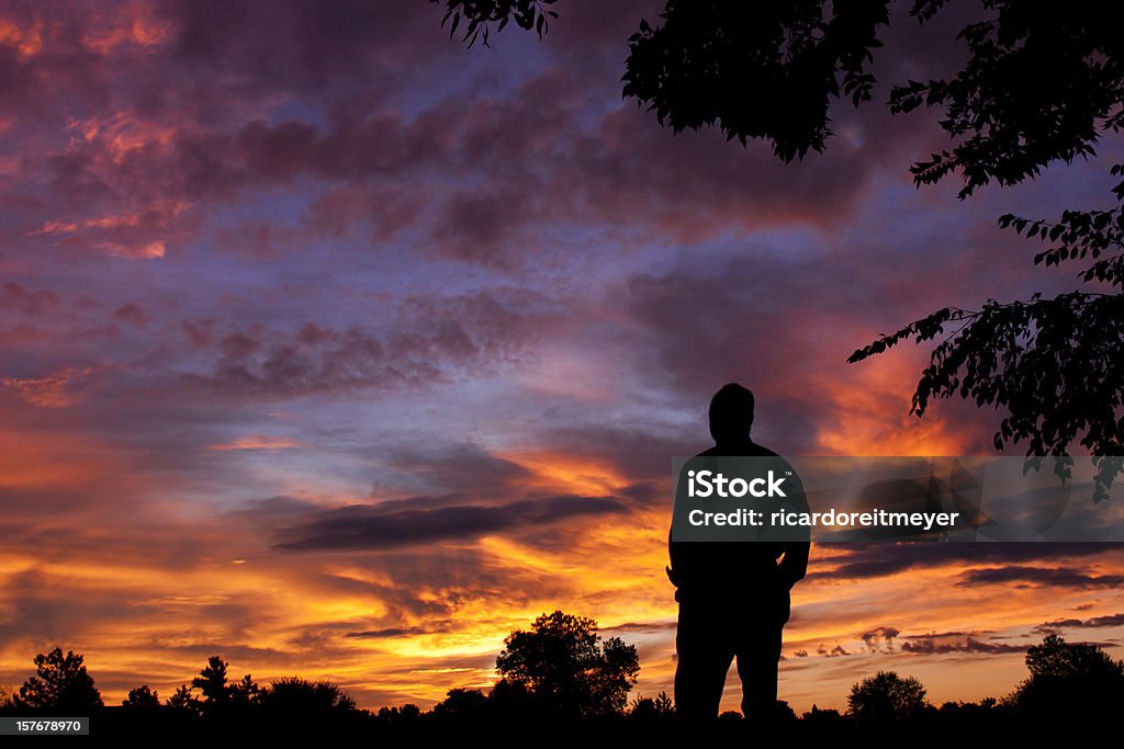 Silhueta de Homem observa espetacular céu durante a colorida do nascer do sol de manhã cedo - Foto de stock de 55-59 anos royalty-free