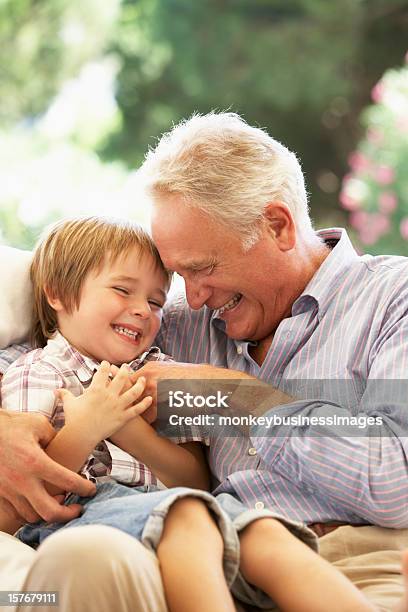 Nonno Con Nipote Ridere Insieme Sul Divano Di - Fotografie stock e altre immagini di Nonno - Nonno, Bambino, Nipote maschio