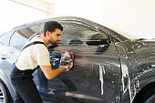 Car wash worker professionally washing customer's car