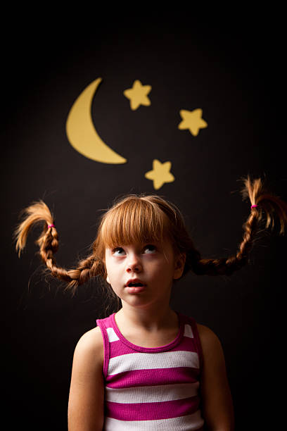 маленькая девочка с косичками глядя вверх в виде луны и звезд - child little girls bizarre pippi стоковые фото и изображения