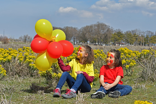 The children are having fun with their yellow and red clothes and balloons.