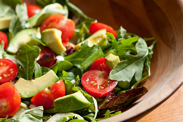A garden salad with lettuce,  avocado slices, and garden fresh tomatoes