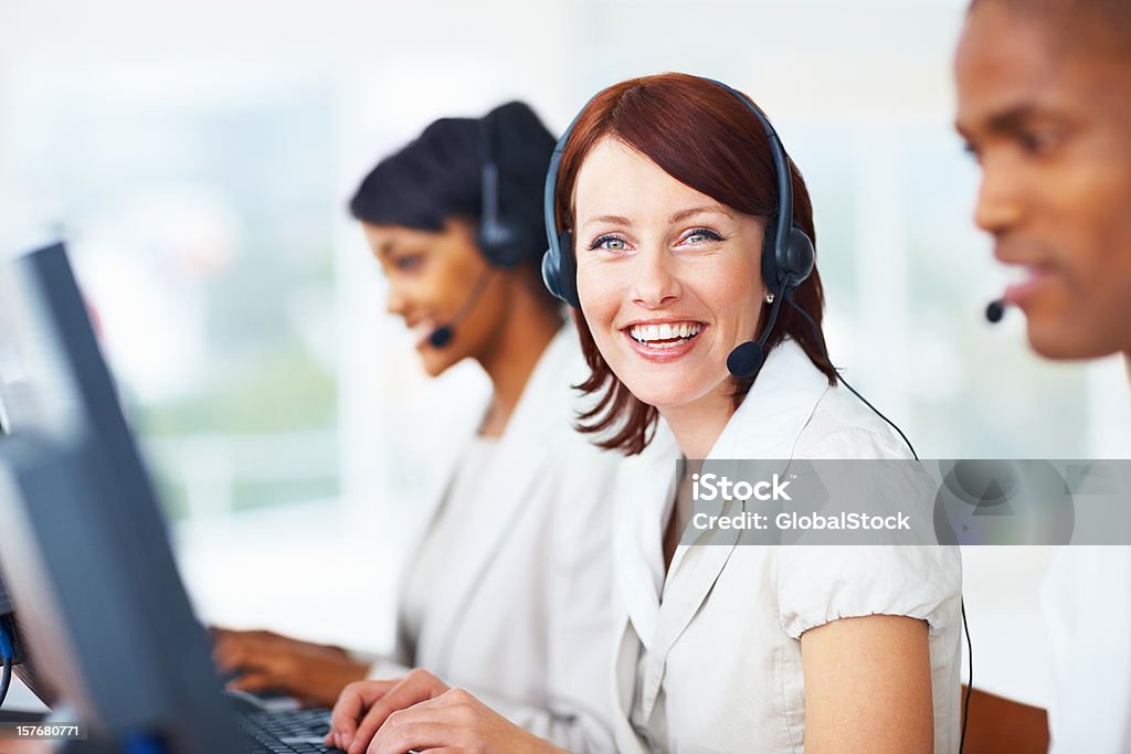 Happy woman with her blur team in a call centre Portrait of a happy woman wearing headset with her blur team in a call centre Adult Stock Photo