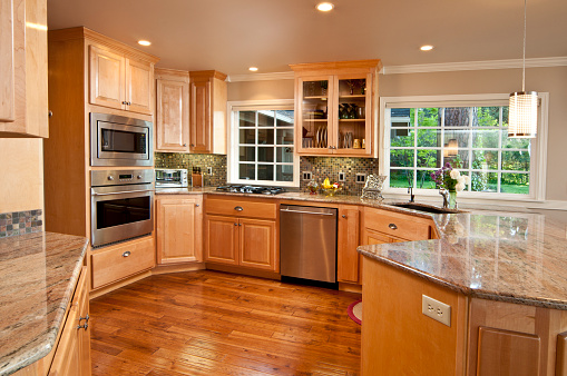 This modern kitchen gives a wide view showing the wood floor and cabinets.