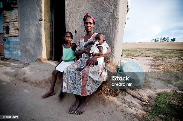 Poor African Family Sitting In Front Of A Shanty Hut Stock Photo - Download Image Now