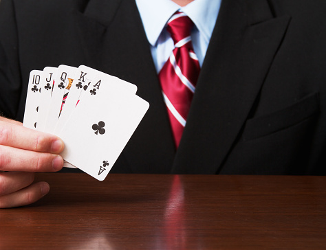 a businessman holding a royal flush card hand.