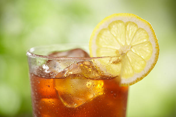A close-up of a glass of iced tea with lemon Tight shot of top of Iced tea in outdoor setting. iced tea stock pictures, royalty-free photos & images