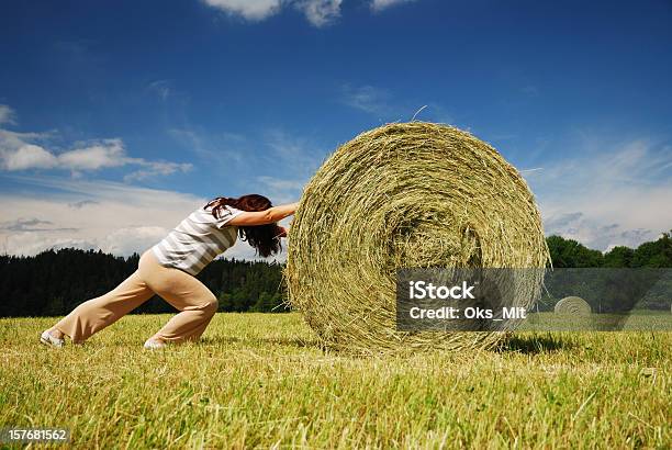 Mujer Empujando Straw Bale En Foto de stock y más banco de imágenes de Adulto - Adulto, Agricultura, Aire libre