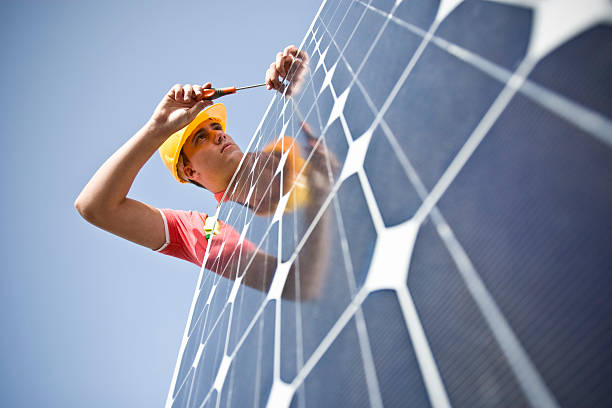 Male worker at work fixing solar panel stock photo