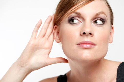 Young woman with cupping hand behind ear and eavesdropping