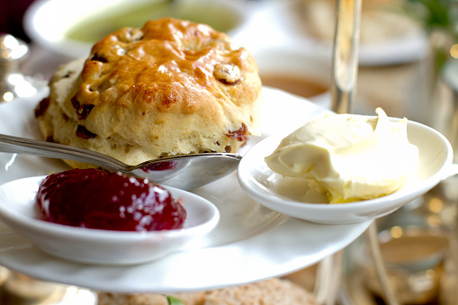 Fancy scone with clotted cream and jam for English style High Tea, shallow depth of field, focus on front of scone.  This image was taken in York, England at a fancy tea house.