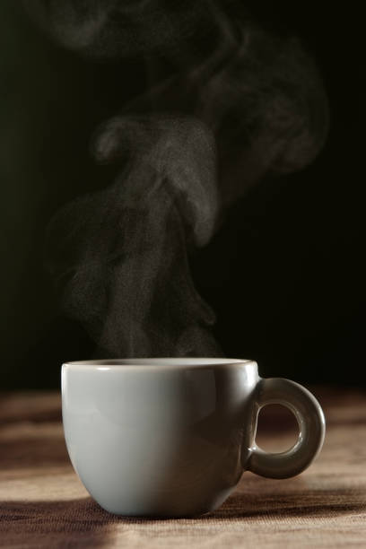 A cup of coffee with steam on brown tablecloth with copy space.