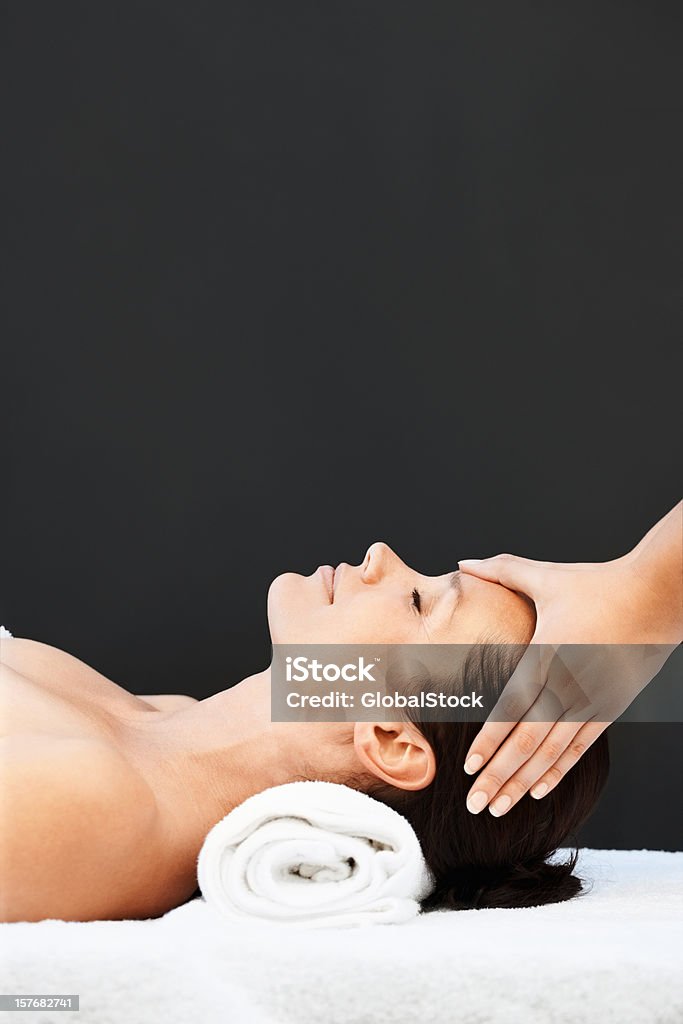 Mid adult woman receiving head massage on black background  Massaging Stock Photo