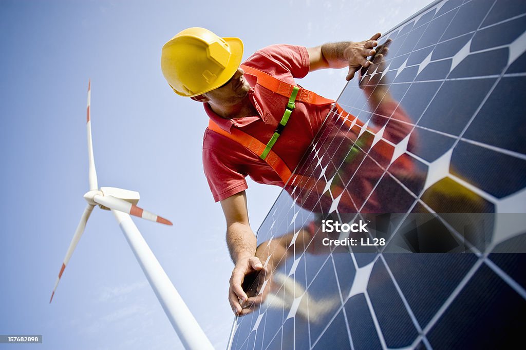 Examination of glass Image of a worker looking at the finishing of a solar panel. In the background you can see Wind Turbines. Two different technologies to produce energy in a responsible and sustainable way (ISO 100) . All my images have been processed in 16 Bits and transfer down to 8 before uploading.  Solar Panel Stock Photo