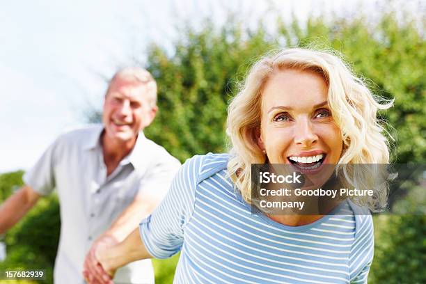 Cheerful Woman Holding Hand Of A Senior Man Against Sky Stock Photo - Download Image Now