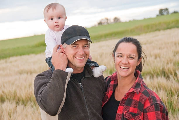Young farming couple with their baby in a barley field. Some visible noise.