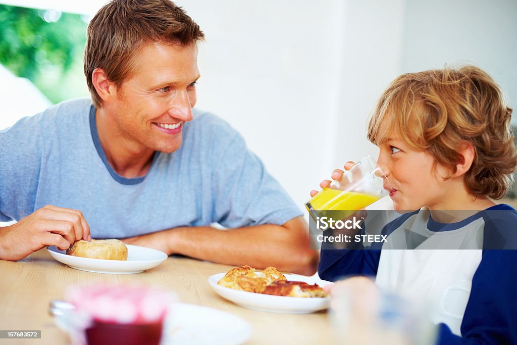 Pai e filho tomando café da manhã enquanto olhando uns aos outros - Foto de stock de 20 Anos royalty-free