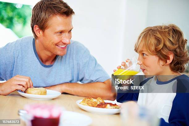 Foto de Pai E Filho Tomando Café Da Manhã Enquanto Olhando Uns Aos Outros e mais fotos de stock de 20 Anos