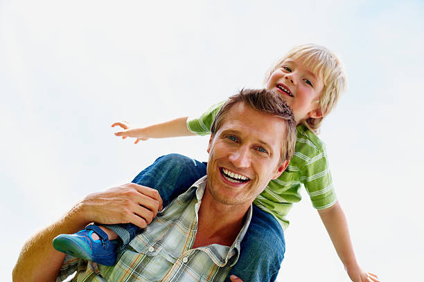 istock Cheerful father carrying his son on shoulders against sky 157683621