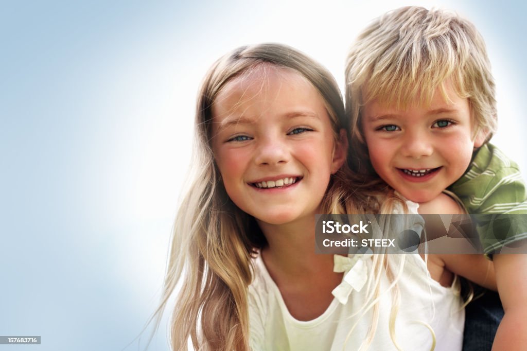 Pretty girl carrying her brother against white  Adolescence Stock Photo