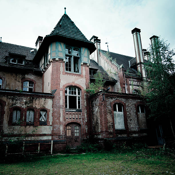 Spooky Abandoned Palace Building Famous abandoned ruined hospital located near Berlin. Broken windows, damaged structure. Desaturated and grainy for the mood. haunted house stock pictures, royalty-free photos & images