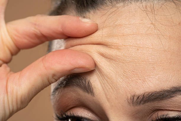 Woman checking her wrinkles on her forehead Woman checking her wrinkles on her forehead. wrinkled forehead stock pictures, royalty-free photos & images