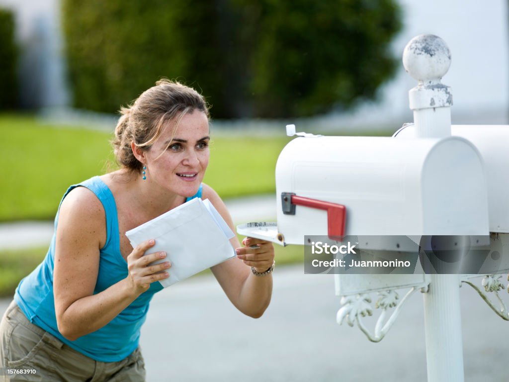 Eine weiße Frau holding Buchstaben-looks in einen Briefkasten - Lizenzfrei Briefkasten Stock-Foto