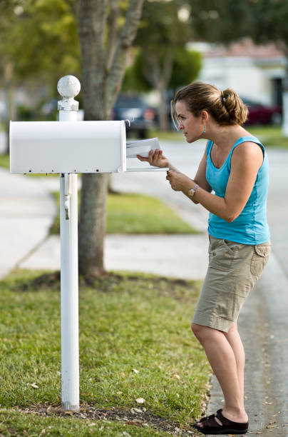 femme de soulever courrier - women suburb mailbox curiosity photos et images de collection