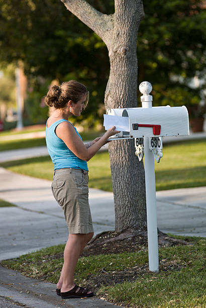 femme de soulever courrier - women suburb mailbox curiosity photos et images de collection