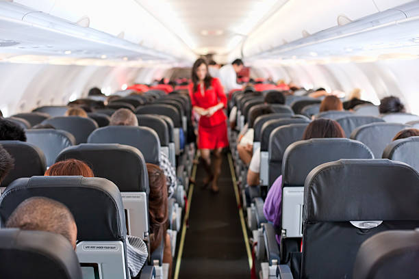 Commercial airliner cabin. Passengers inside the cabin of a commercial airliner during flight. Shallow depth of field with focus on the seats in the foreground. passenger cabin photos stock pictures, royalty-free photos & images