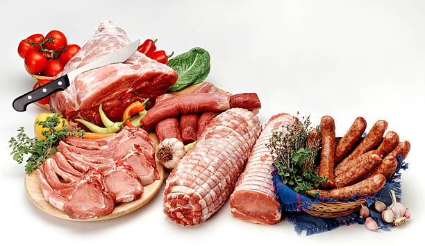 Fresh butcher cut meat assortment garnished with fresh vegetables and aromatic herbs.