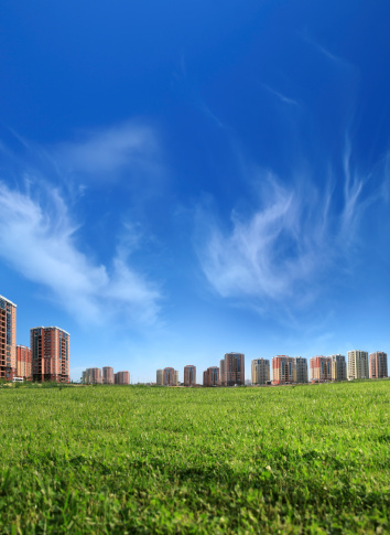 residential buildings on green landscape over clear sky.