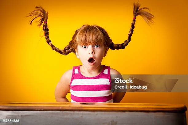 Sorprendido Niña De Pelo Roja Con Mallas Para Arriba En La Escuela Escritorio Foto de stock y más banco de imágenes de Niño