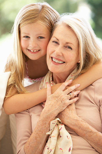 abuela con granddaughter sonriente en sofá - 70st fotografías e imágenes de stock