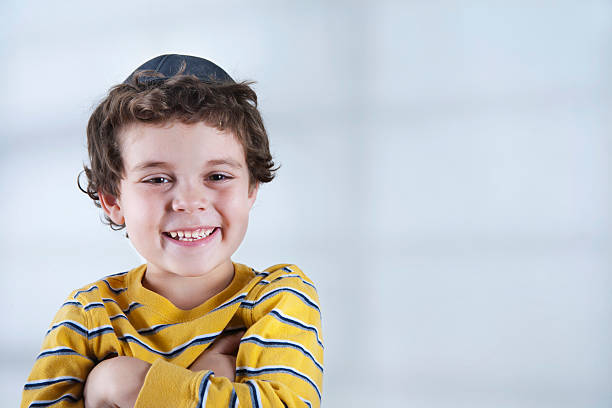 Smiling Jewish boy in striped yellow shirt A young Jewish boy wearing a yarmulke, looking at the camera. yarmulke photos stock pictures, royalty-free photos & images