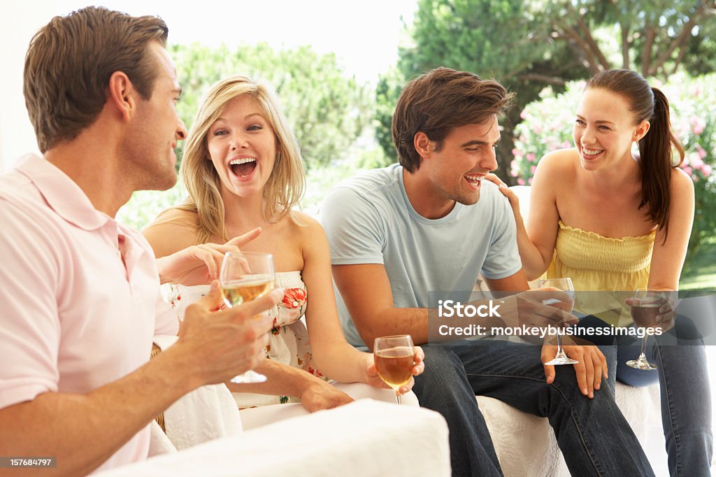 Grupo de jóvenes amigos descansando en el sofá bebiendo vino juntos - Foto de stock de 20 a 29 años libre de derechos