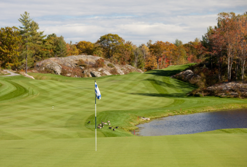 A beautiful golf course in the fall. Ontario, Canada. Muskoka region. A beautiful par-5 golf hole scenic of a classic parkland golf course in this cottage country region. Themes include golf, gravenhurst, Ontario, sports, game, leisure, landscape, nobody, flagstick, turf, pond, golf green, fairway, and maintenance. Nobody is in the image, taken with Canon Mark II 5D body and L series lens. 
