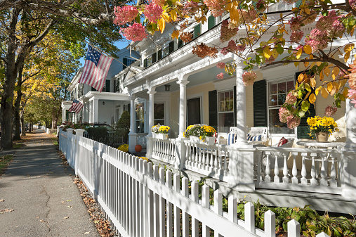 A view of some antique houses, dappled with warm autumn sunlight, in the charming town of Woodstock, Vermont.
