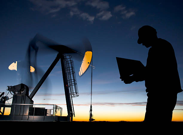 Poço de Petróleo Pumpjack ao amanhecer com trabalhador - foto de acervo