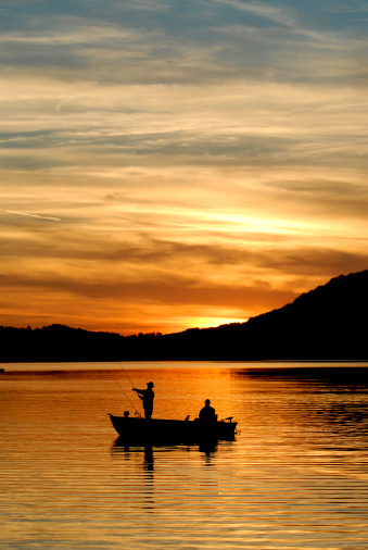 Two fisherman's silhouettes with beautiful sunset.