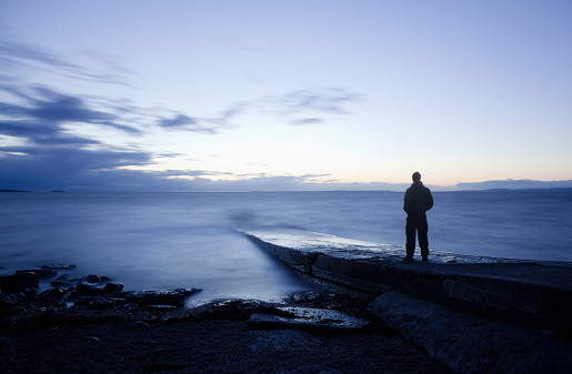 Silhouette of adult man walking on beach during sunrise. Cabo de Gata Nature Park, Almeria, Spain